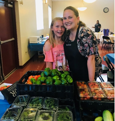 an adult and child stand by vegetables that are being grown