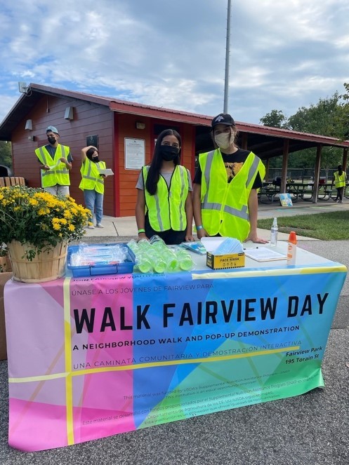 participants from the Walk Fairview Day stand behind a table with a sign