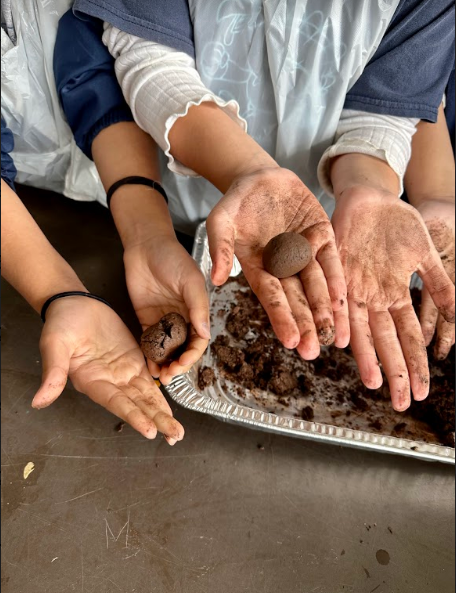 Students proudly show their finished seed balls and soiled hands