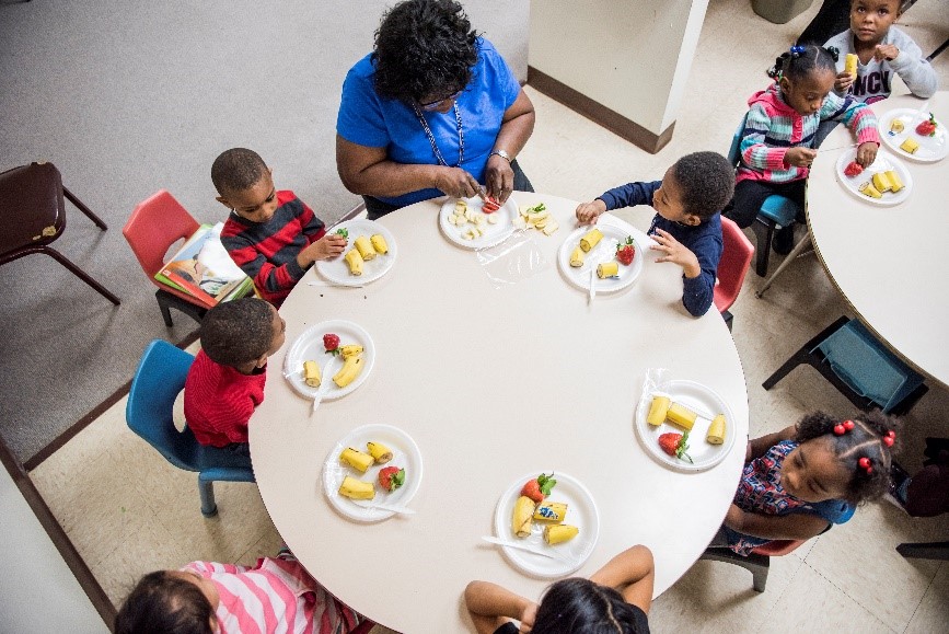 preschoolers and a teacher sharing a meal around a table