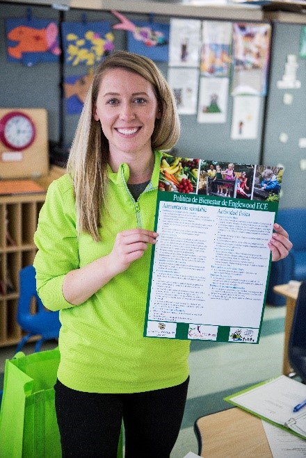 A staff member holding a wellness policy poster.