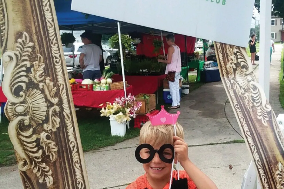 girl with glasses holding a sign "POP Power of Produce Club"