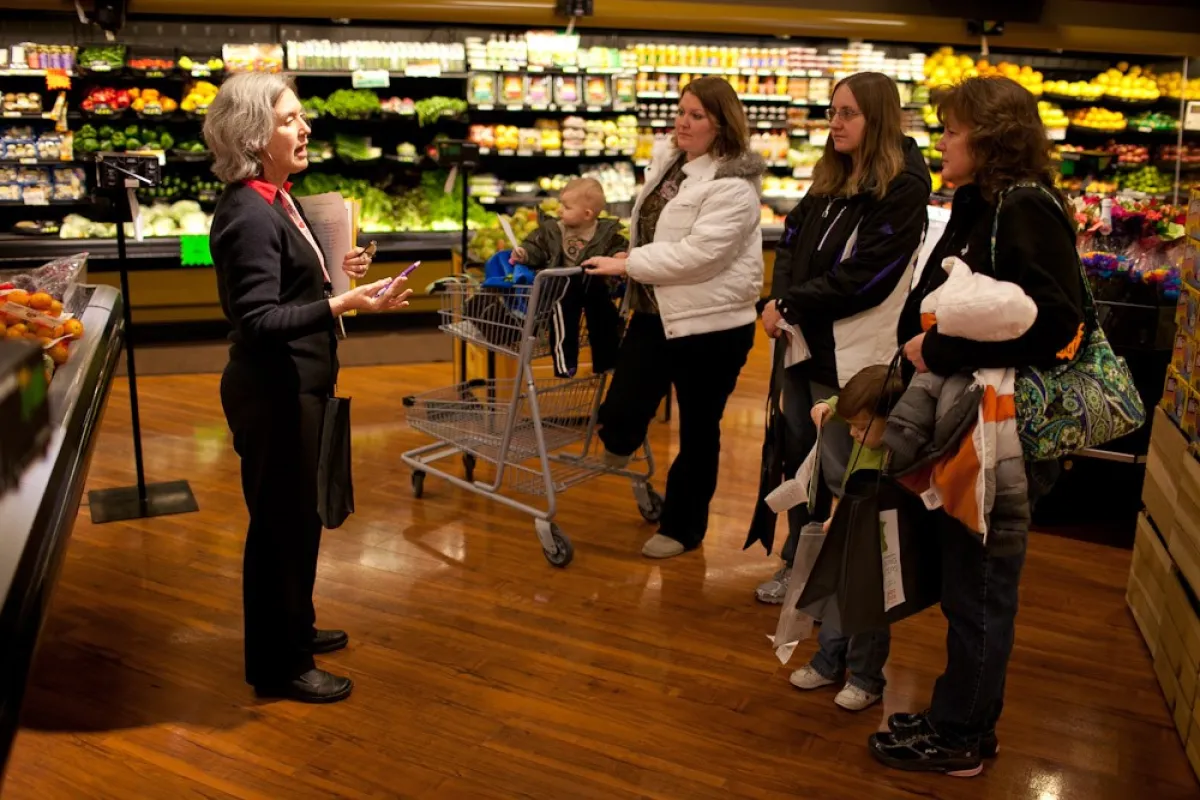 an educator talks to a group of adults in a grocery store