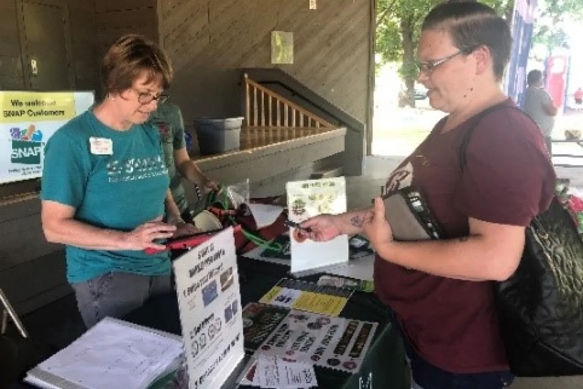 customer interacts with snap-ed booth at a farmers market