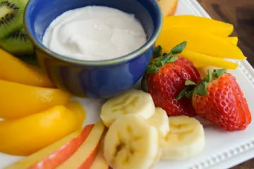 Fruit on a plate with dip in a blue bowl