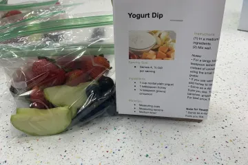 creating activity kits for pickup by camp participants: fruit and veggies in a plastic bag with a recipe attached