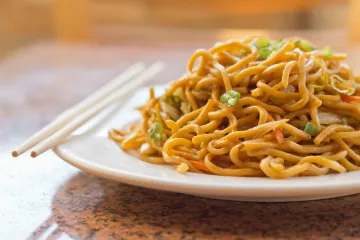 fried noodles on a plate with chop sticks