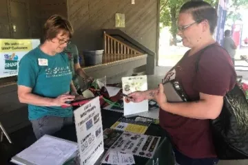 customer interacts with snap-ed booth at a farmers market