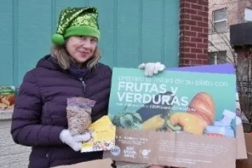 A food pantry worker holds up a sign in Spanish