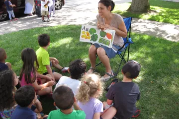 women reading a book about produce to a group of children