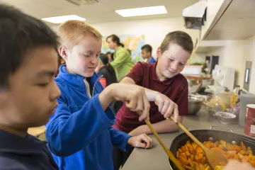 boys stirring food in a skillet