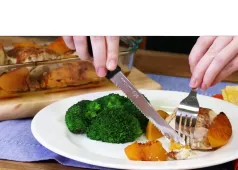 cutting food on a plate of broccoli and peaches