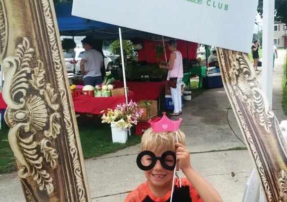 child wearing glasses holding a sign "POP Power of Produce Club"