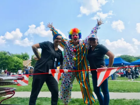 a clown poses with 2 women
