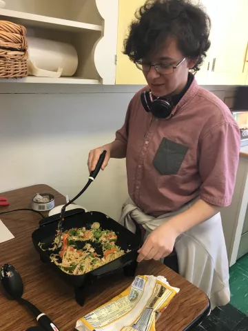 a teen cooks using an electric skillet