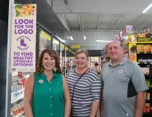 Sign in a store: "Look for the Logo (Geaux Shop Healthy) To find healthy affordable options! next to 3 adults standing in a grocery aisle