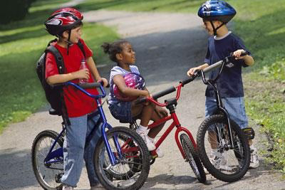 three kids riding bikes outside to school